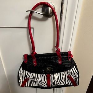 Animal hair zebra print bag with red and black leather trim. Silver buckle front